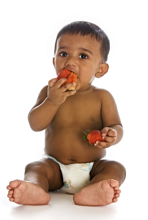 A Black baby eating strawberries