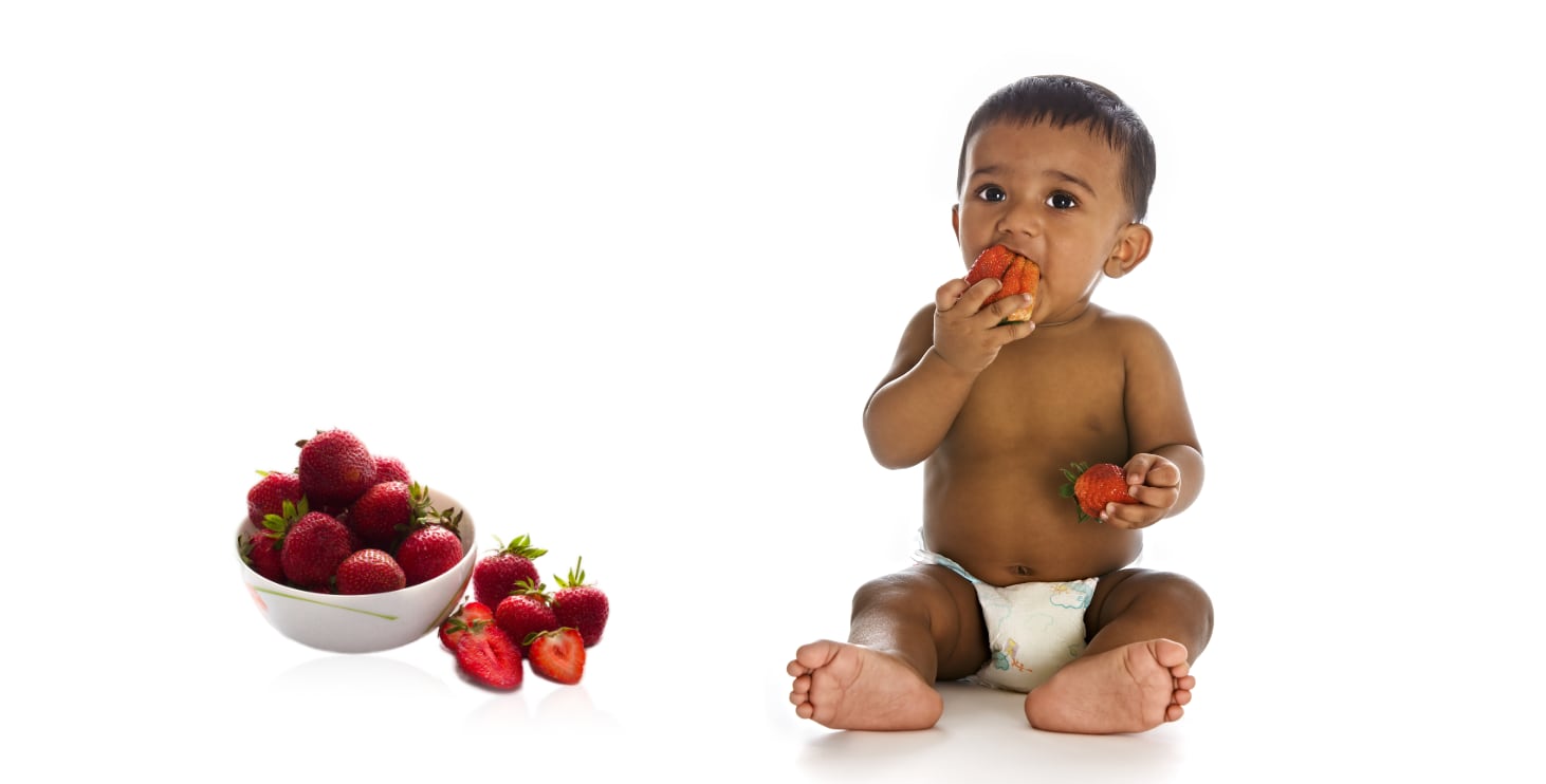 A Black baby eating strawberries