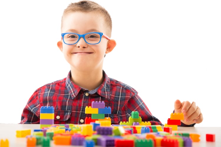 A young boy with Down syndrome plays with Legos