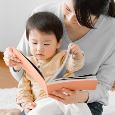 An Asian mother with her toddler, flipping through a picture book