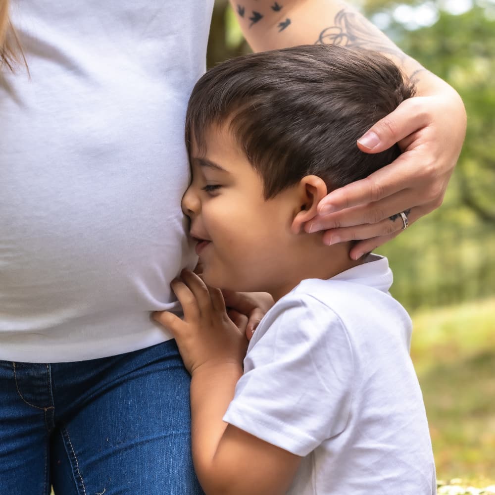 A young boy snuggles with his pregnant mother